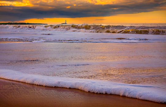 Waves Breaking on the Shore and a Lighthouse in Distance 
