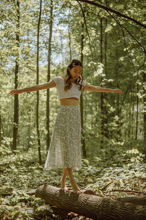 Free Graceful ethnic woman balancing on trunk in grove Stock Photo