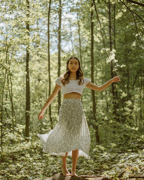 Asian woman balancing on trunk in woods