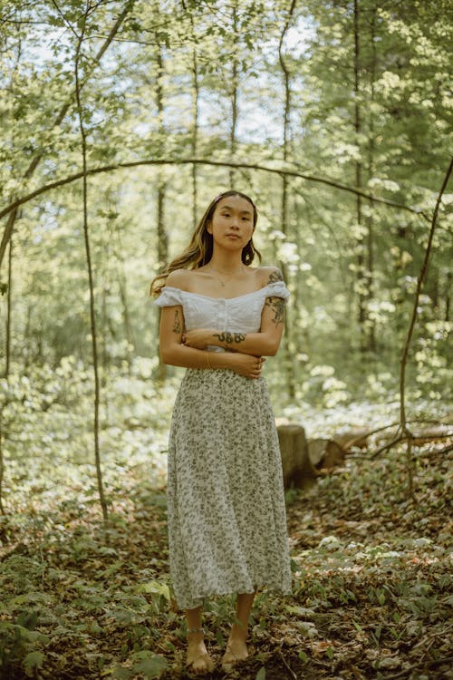 Asian woman embracing herself in sunny woods