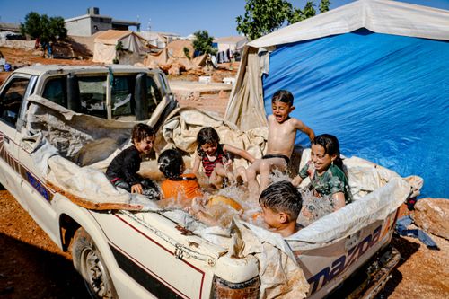 Free Children having fun in a makeshift pool in a pickup truck in Idlib, Syria, during summertime. Stock Photo