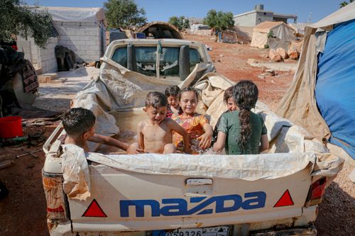 Free Joyful children enjoy a makeshift pool in a camp in Idlib, Syria under the sun. Stock Photo