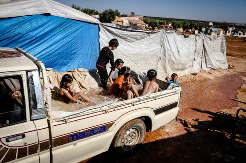 Free Children enjoying water play in a truck bed, village setting in Idlib, Syria. Stock Photo