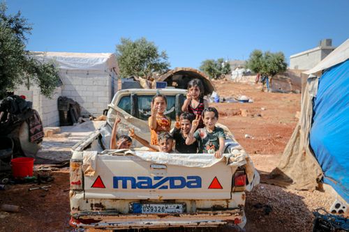 Free Children play in a truck in an Idlib village, capturing a joyful summer moment. Stock Photo