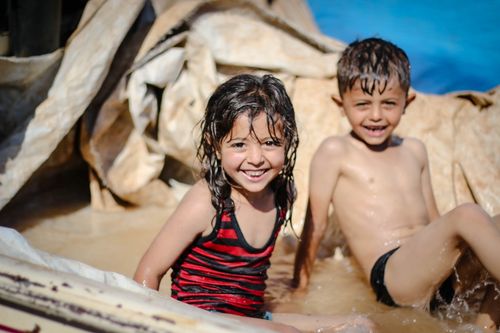 Free Happy children enjoying a splash of water on a sunny day in Idlib, Syria. Stock Photo