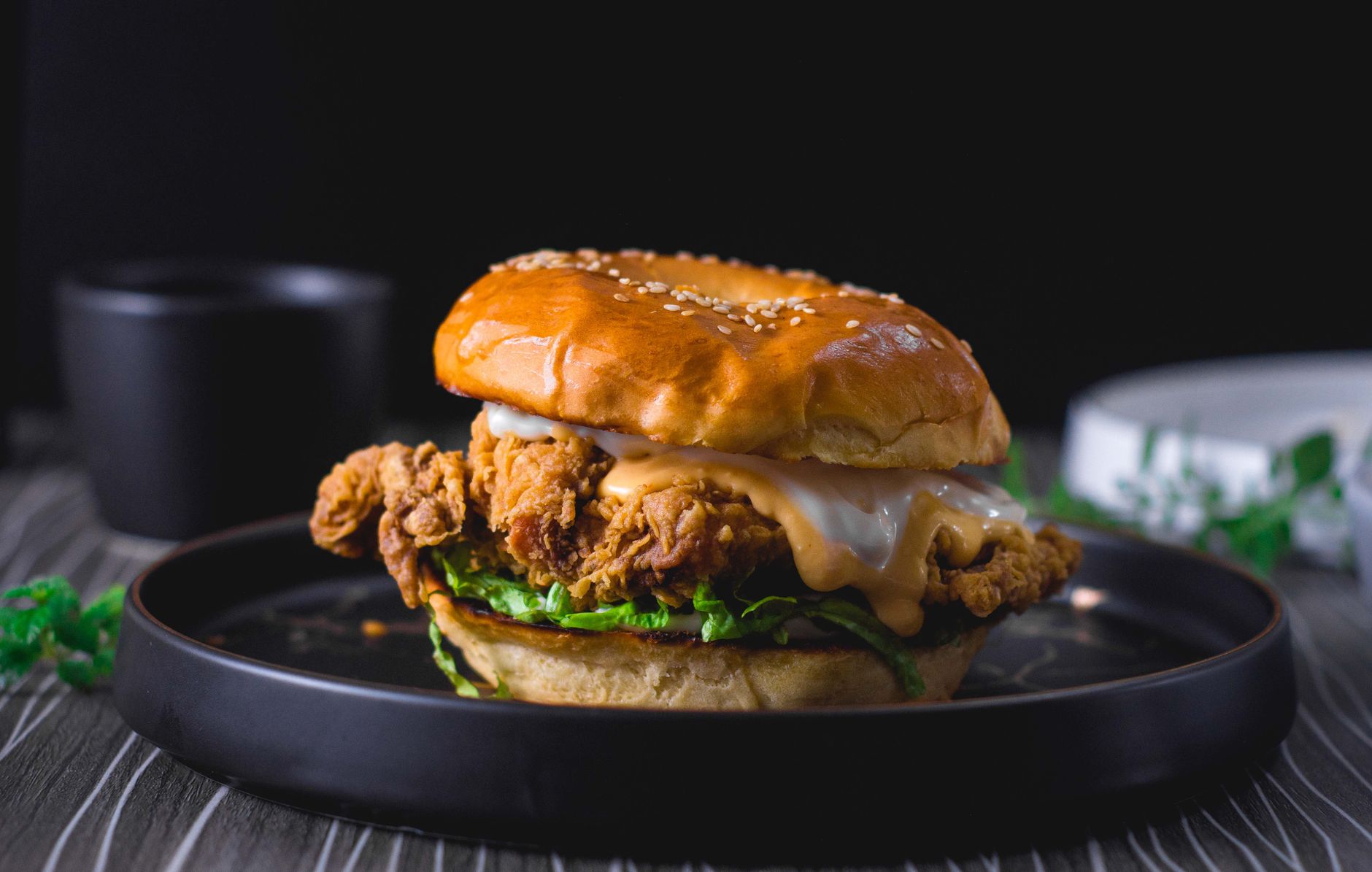 Golden-brown panko-crusted chicken katsu burger on a brioche bun with shredded cabbage and creamy spicy mayo, garnished with sliced scallions