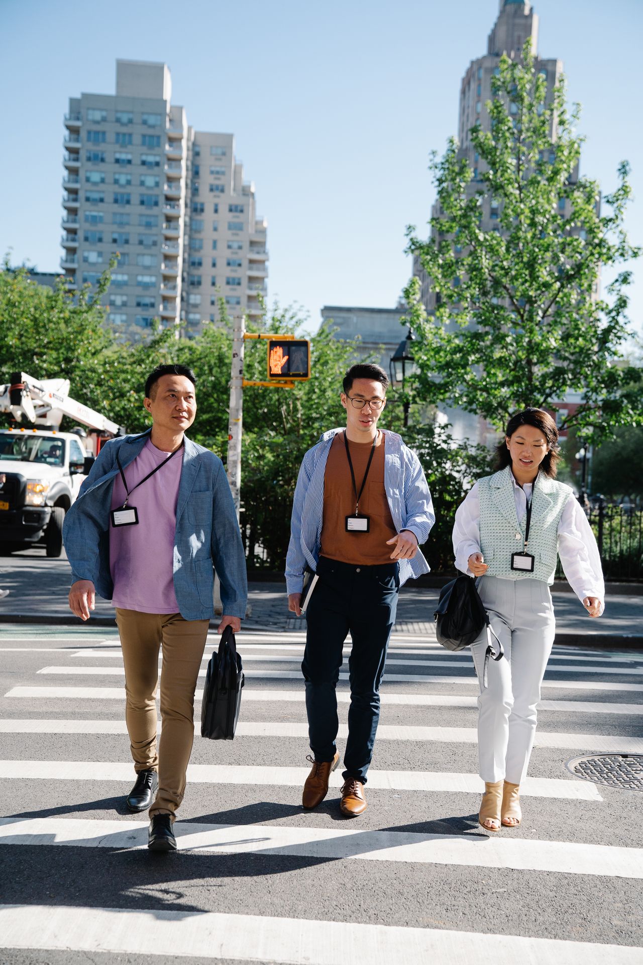 Three professionals crossing a busy urban street on a sunny day, showcasing teamwork and diversity