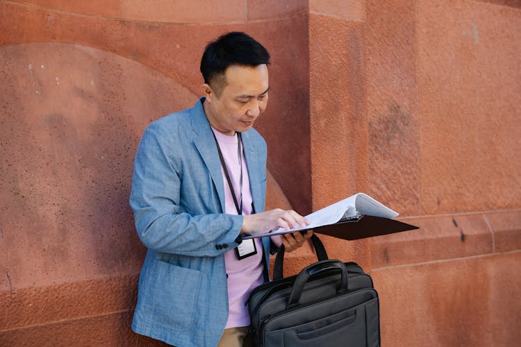 Man In Blue Suit Jacket Holding A Binder