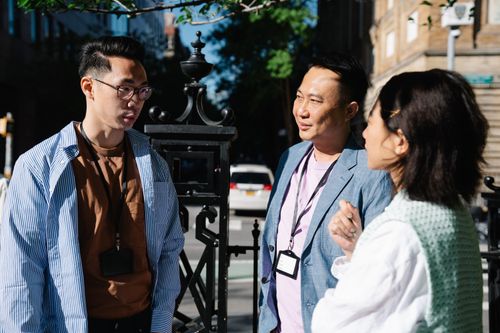 Free Three adults having a casual discussion outdoors during the day. Stock Photo