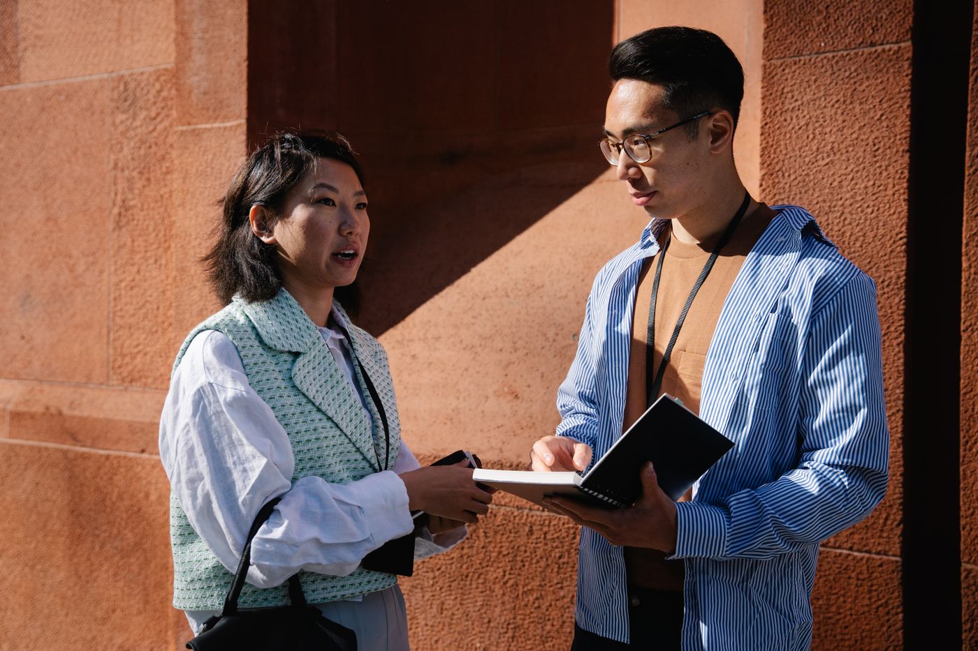 Two people in discussion outdoors against an orange wall