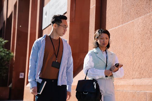 Man and Woman Walking along Building