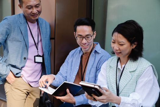 Group of diverse adults engaged in a collaborative tech-based meeting outdoors.