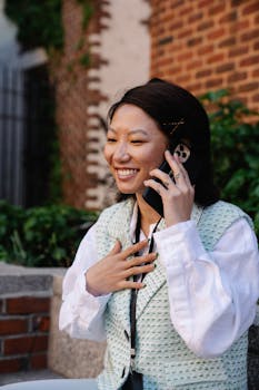 Smiling woman happily talking on her smartphone in an outdoor setting.