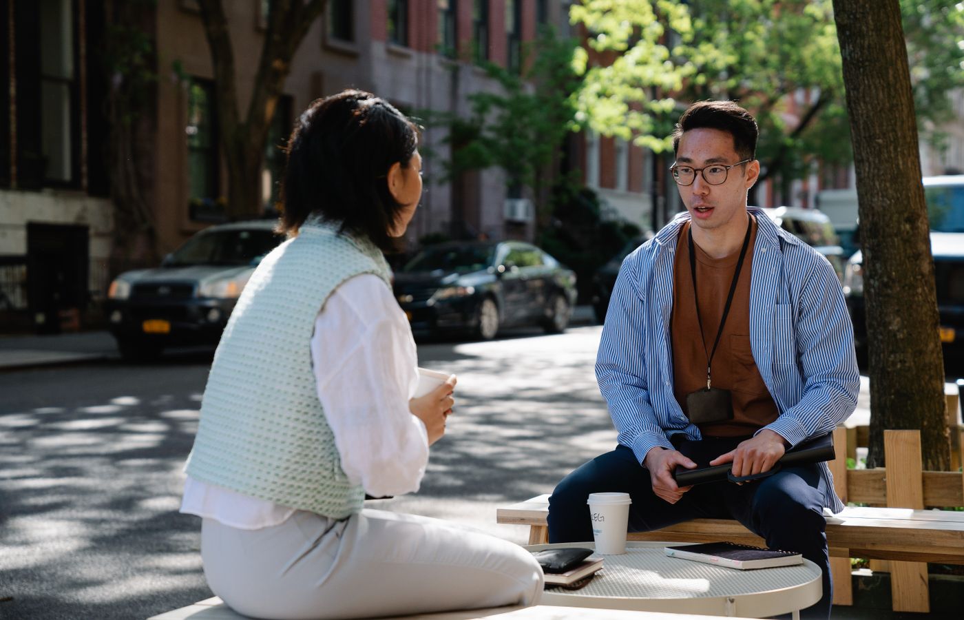 Two colleagues engaged in a conversation outdoors on a sunny day in an urban street.