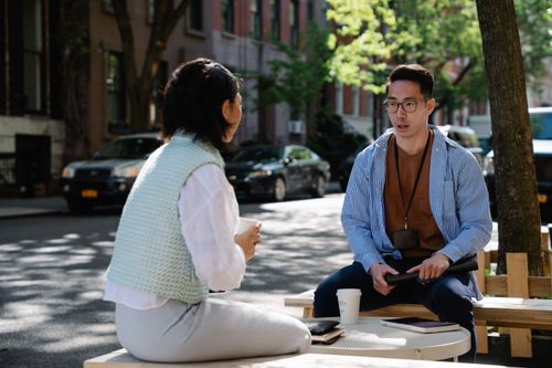 Free Two colleagues engaged in a conversation outdoors on a sunny day in an urban street. Stock Photo