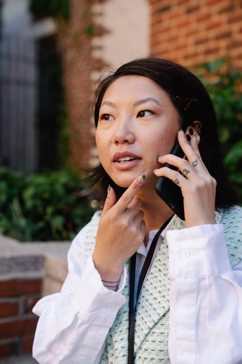 Close-Up Shot of a Woman With Finger Tattoos Talking on The Phone