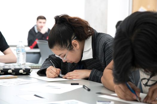 Students intensely focused on writing during a classroom activity, demonstrating concentration and study.