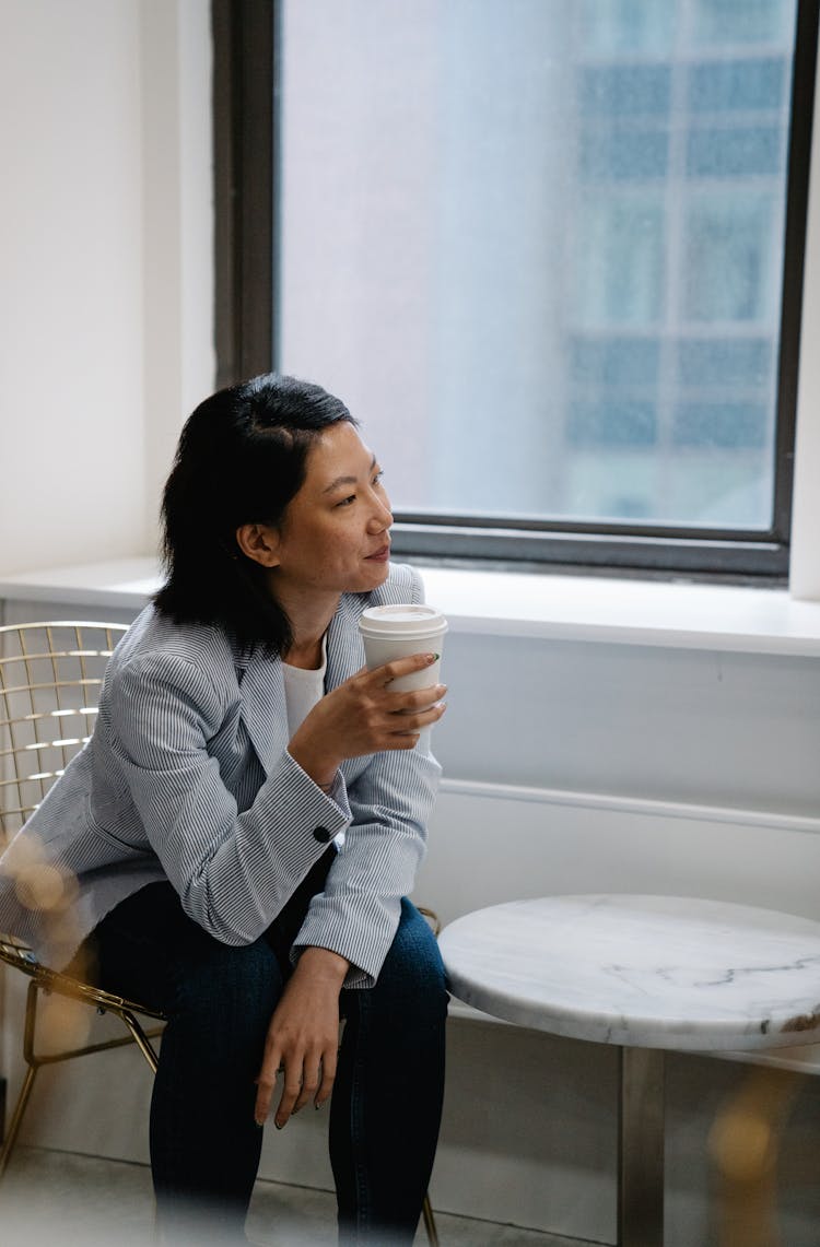 Woman Sitting In Cafe Drinking Coffee