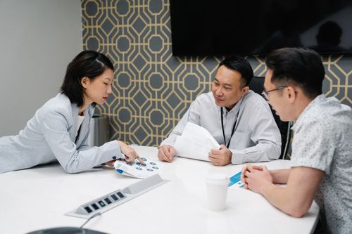 Free Professional team engaged in discussion around office desk, focusing on documents and collaboration. Stock Photo