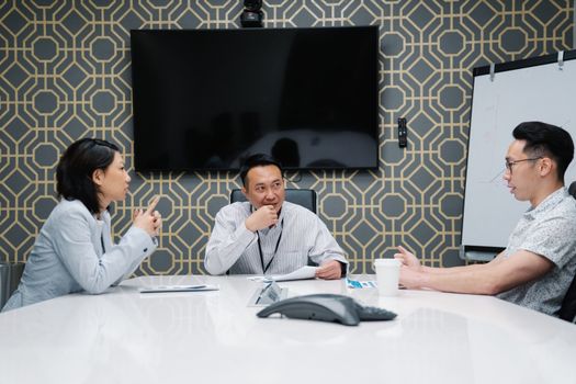 Three professionals engaged in a meeting in a modern conference room.