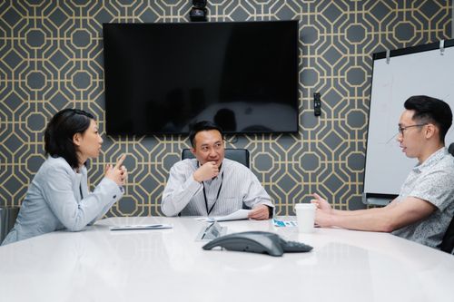 Free Three professionals engaged in a meeting in a modern conference room. Stock Photo