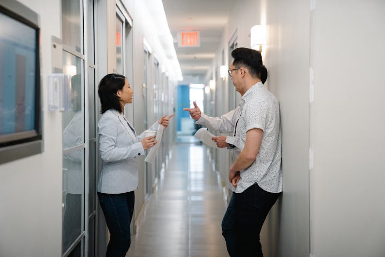 Woman In Gray Blazer Talking To Two Men In The Hallway Of The Office