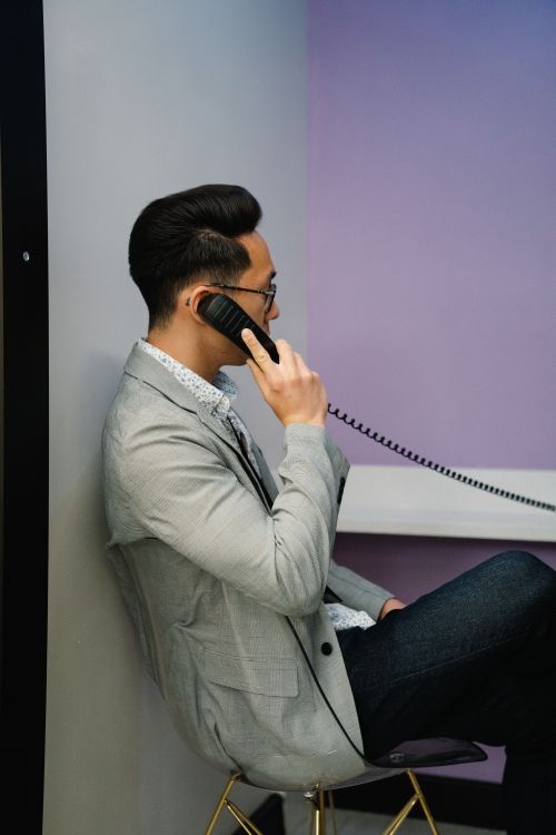 Free Businessman engaged in a phone call, wearing glasses and blazer indoors. Stock Photo