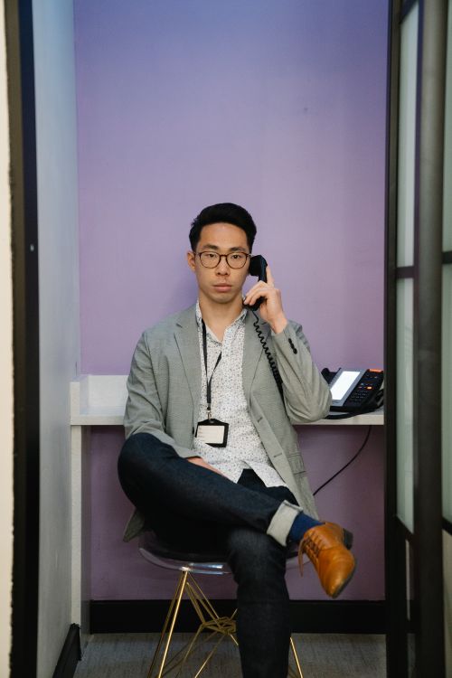 Free Confident young man in a small office booth making a phone call, dressed in business attire. Stock Photo