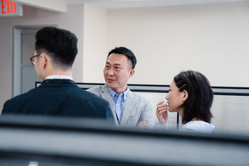 Free Three professionals engaged in a conversation in a bright, modern office setting. Stock Photo