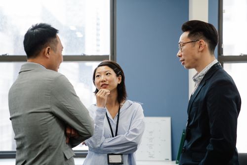 Free Three business colleagues engage in a thoughtful discussion in a modern office setting. Stock Photo