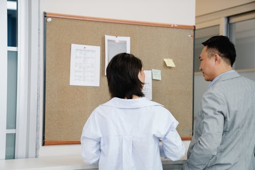 Free Man and a Woman Talking in Front of a Bulletin Board Stock Photo