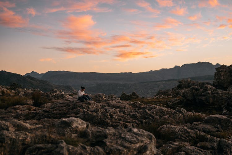 Person Sitting On Rocky Mountain Area