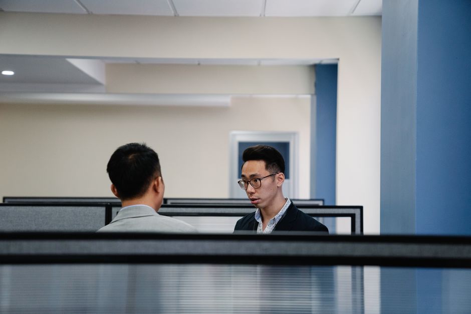 Two professionals in attentive conversation in an office, one listening to the other