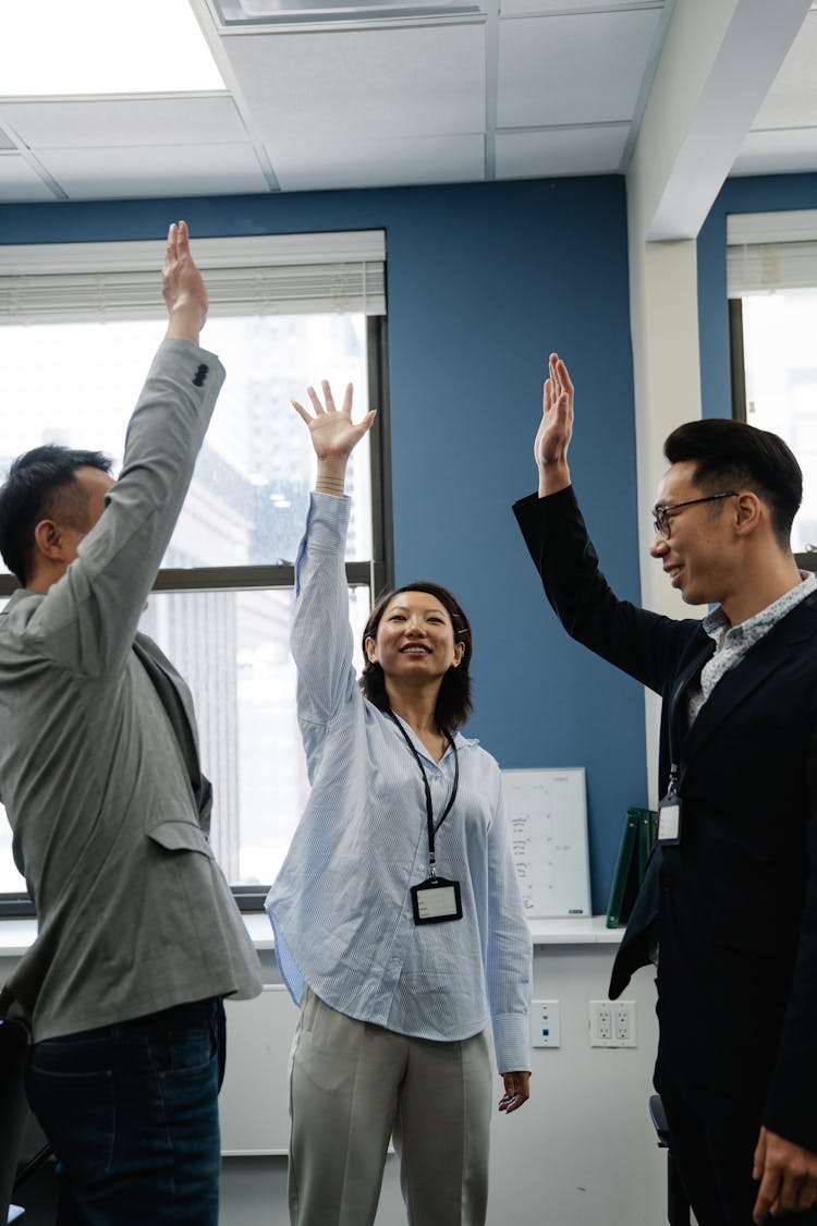 Photograph Of A Group Of Employees Raising Their Hands