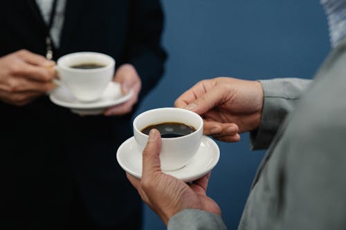 Photo of a Person's Hands Holding a Cup of Black Coffee