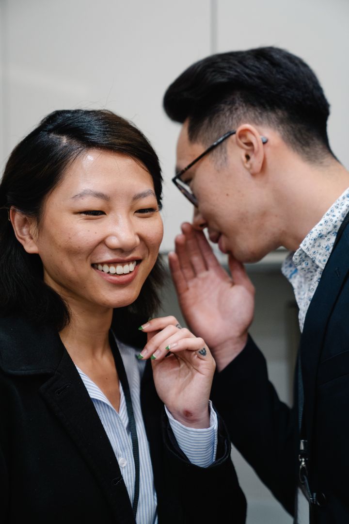 Two colleagues sharing something in confidence at work. Photo by Felicity Tai on Pexels