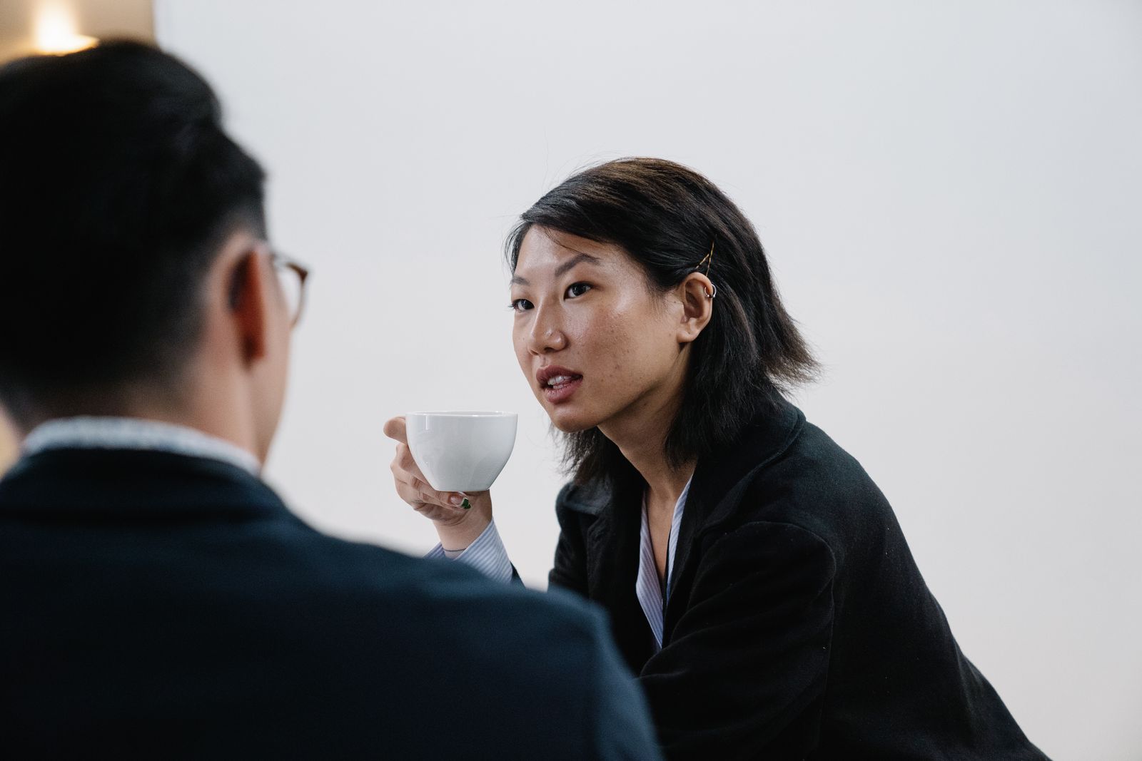 Two Anorthite colleagues in conversation over coffee against a plain daylit wall. Photo by Felicity Tai on Pexels.
