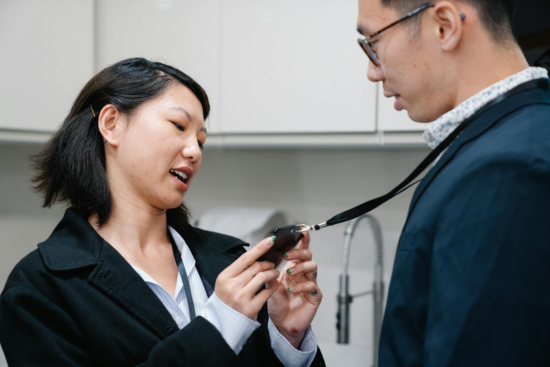 Two colleagues in an office setting discuss an identification badge, showcasing teamwork and communication.