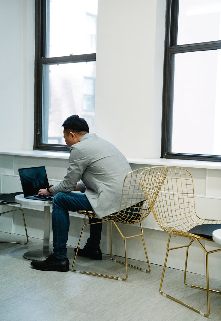 Back View Of A Man Wearing A Suit Sitting On A Corridor With A Laptop