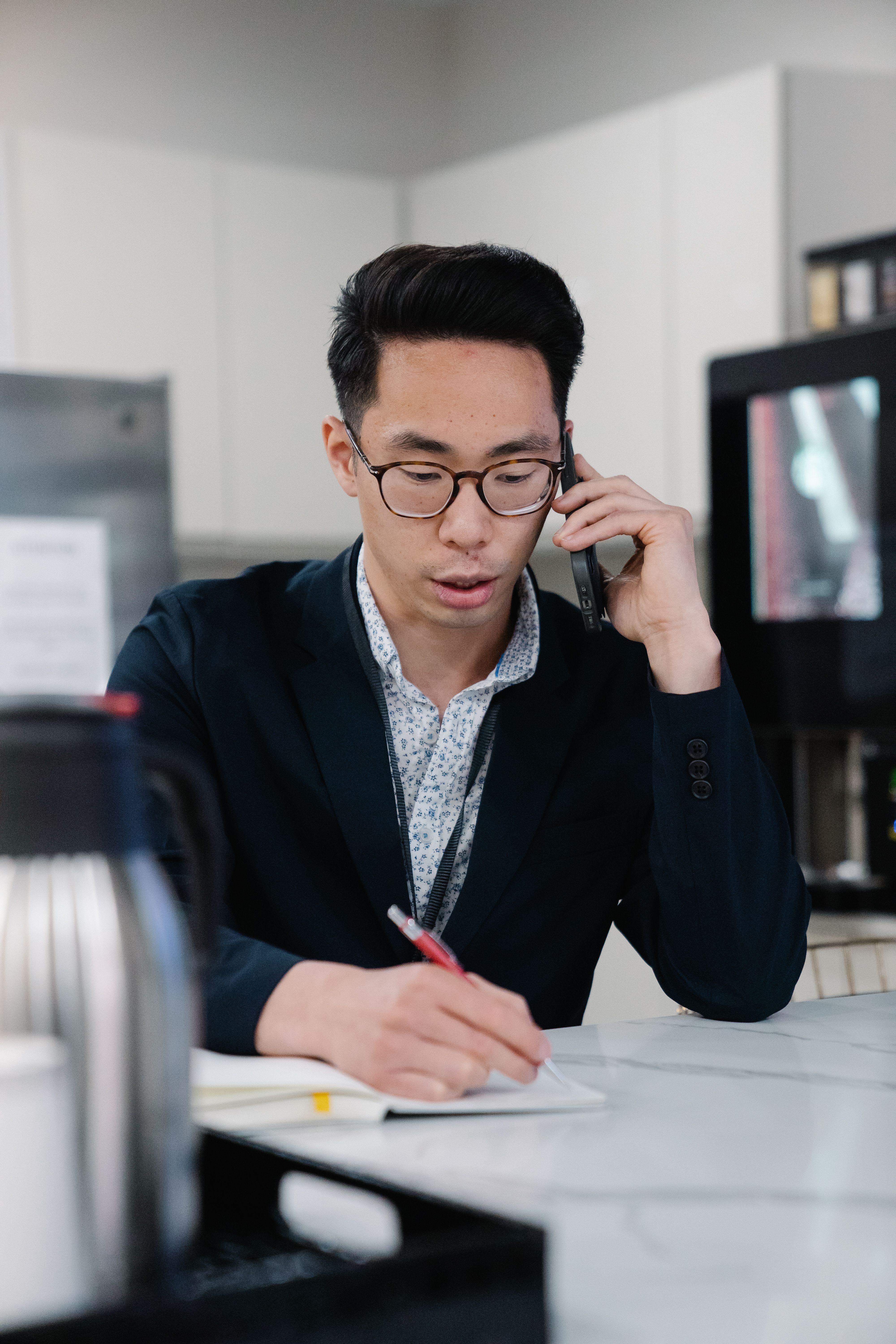 IMAGE 4:5 — THE PHONE HUNT: an ALIGN recruiter taking notes on a call with a currently-employed executive in a modern office