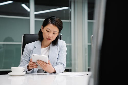 Businesswoman Sitting by Desk with Tablet