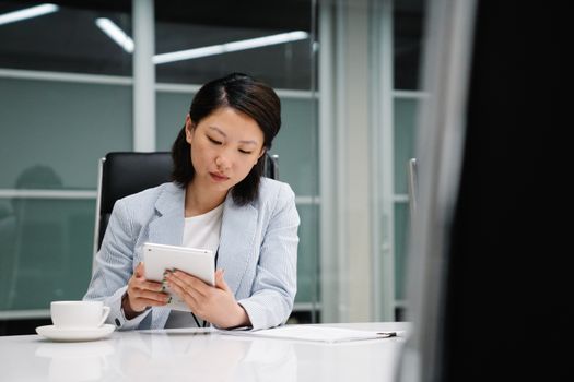 Professional businesswoman working on a tablet at a sleek office desk.