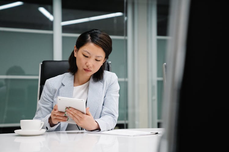 Businesswoman Sitting By Desk With Tablet