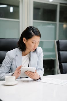 Confident woman using a tablet at the office desk, focusing on work tasks.