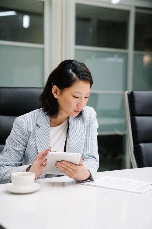 Free Confident woman using a tablet at the office desk, focusing on work tasks. Stock Photo