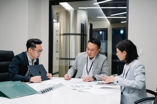 Free Business meeting with three professionals collaborating in a modern conference room setting. Stock Photo