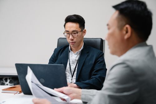 Free Two business professionals focused during a meeting, working on laptops and documents. Stock Photo