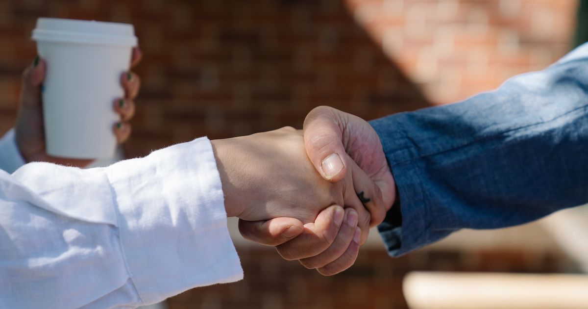 A professional shaking hands with a community member at a networking event.