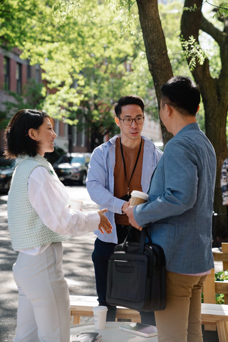 People Greeting Each Other By A Coffee Table On A Sunny Street