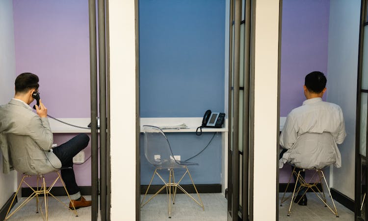 Men Sitting On Telephone Booths